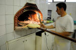 27. ...mentre il forno dove hanno appena finito di cuocersi le pizze comincia a ricevere nuove pagnotte.