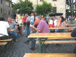 16. La piazza si riempie, e ai tavoli, mentre qualcun altro fa la fila per loro, molti attendono conversando amabilmente...
