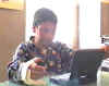 Primo piano del professor Sandro, che apre un computer portatile e comincia a digitare.